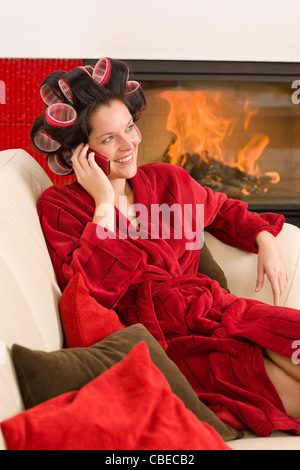 Home Schönheit Frau mit Lockenwickler anrufen Telefon Kamin roten Bademantel Stockfoto