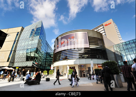 Eröffnungstag im Westfield Stratford City Shopping Centre, London. Shopper genießen die Sonne und blauer Himmel vor John Lewis Geschäft. Stockfoto