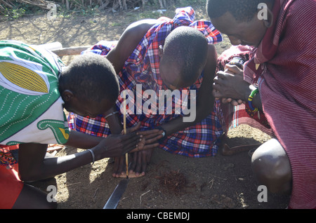 Kenia, Masai Mara, Mitglieder des Stammes Masai unterhalten Touristen durch ein Feuer anzündet Stockfoto