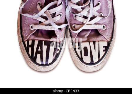 Jugendliche, die mit den Worten Converse Schuhe angepasst Hass und Liebe auf weißem Hintergrund Stockfoto