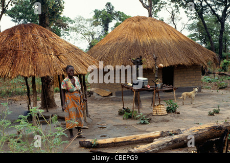 Lukulu, Sambia, Afrika. Junge Frau vor ihrem Haus im Dorf und Küche mit ihrem Hund. Stockfoto