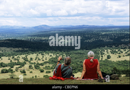 Olenkapune, Kenia. Mittelalterlichen weißer Tourist paar ruht auf einem Hügel mit Blick auf das Rift Valley in der Maasai Mara zu reservieren. Stockfoto