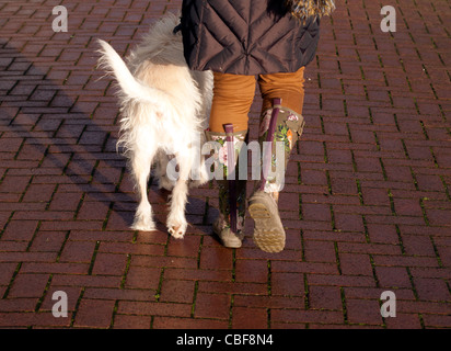 Eine Frau trägt Gummistiefel in Fleetwood während des Gehens eines Hunds Stockfoto