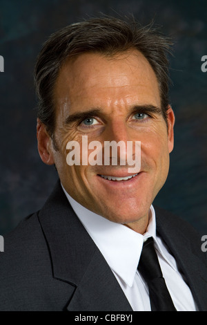 Kopfschuss von mittleren Alter Geschäftsmann trägt einen Mantel und Krawatte lächelnd. Stockfoto