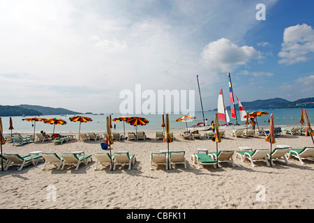 Urlaub-Strand-Szene mit Sonnenliegen und Sonnenschirme am Sandstrand von Patong Beach, Patong, Phuket, Thailand Stockfoto