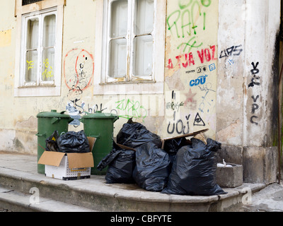 Müllsäcke, gestapelt auf dem Bürgersteig neben einer Wand mit graffiti Stockfoto