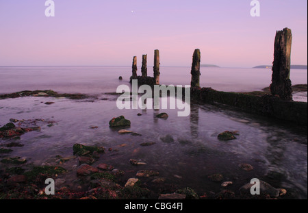 Alte Beiträge stehen unter die Wäsche von der Tide in der Abenddämmerung steigt entlang der Südküste von Irland in Cork. Stockfoto