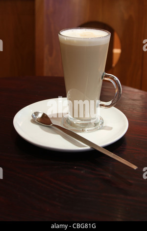 Kaffee Latte in ein hohes Glas auf einem Holztisch mit einem langen Löffel Stockfoto