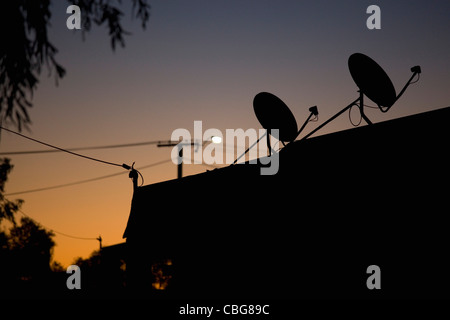 Silhouette Satellitenschüsseln auf dem Dach, Dämmerung Stockfoto