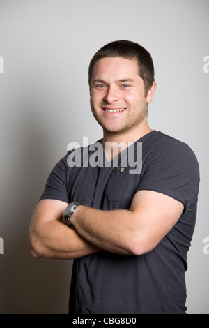 Porträt von zuversichtlich, lächelnden jungen Mann mit Armen gekreuzt Stockfoto