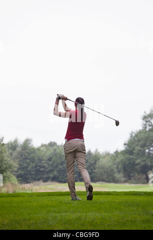 Eine Golfspielerin Abschlag, Rückansicht Stockfoto