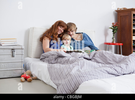 Eine junge Familie im Bett und las ein Bilderbuch Stockfoto