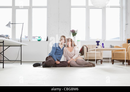 Ein junges Ehepaar nebeneinander auf dem Boden sitzend Stockfoto