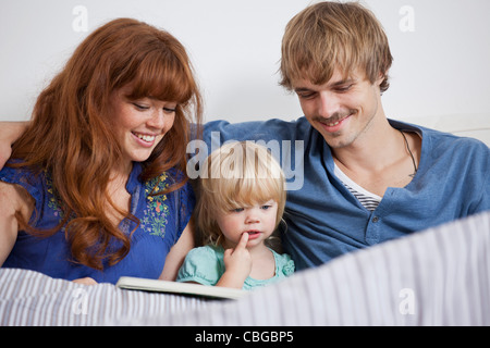 Eine junge Familie, die ein Bild-Buch im Bett lesen Stockfoto