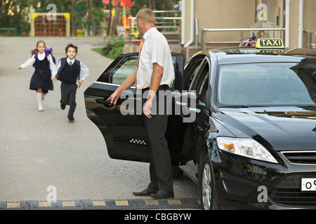 Zwei Kinder in Schuluniformen läuft auf schwarzen Taxi Stockfoto