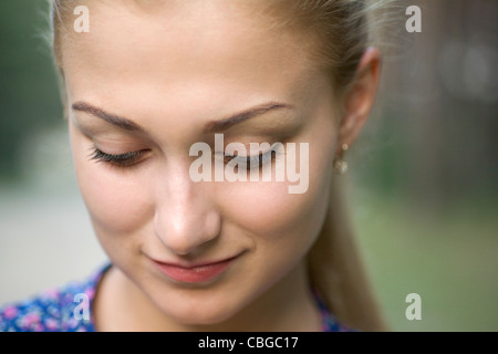 Eine hübsche junge Frau sucht verschämt nach unten, Nahaufnahme Stockfoto