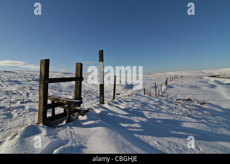 Ein Stil über einen hohen Zaun im tief Schnee bedeckt Pennine Hills Stockfoto