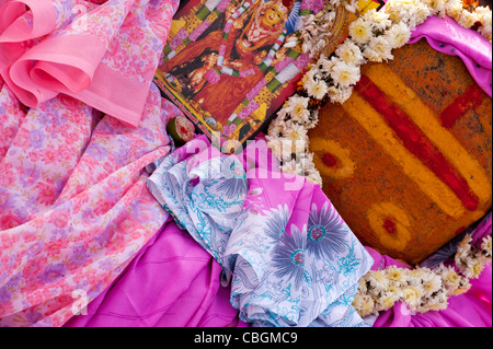 Weibliche hinduistischen Gottheit Tempel Heiligtum Stein mit Blumen Saris und ein Bild geschmückt. Indien Stockfoto