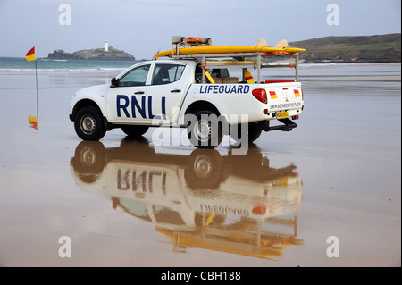 Ein RNLI Rettungsschwimmer Rettung LKW mit Surfbrett an einem Sandstrand. Rettungsfahrzeuge mit Sand und Meer. Stockfoto