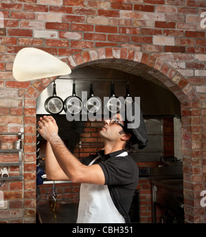 Pizzabäcker macht den Pizzateig Drehung in der Luft zu machen, dünn und weich Stockfoto