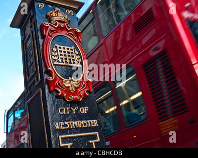 Verzierten historischen Post Marker mit heraldischen Wappen 1902 und roten Bus Grenze Eingang City of Westminster London UK Stockfoto