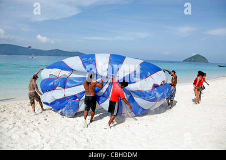 Touristen genießen Sie sportliche Aktivitäten, parasailing mit einem Schnellboot und Fallschirm auf Coral Island, Phuket, Thailand Stockfoto
