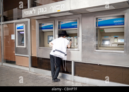 Orthodoxer Jude tragen Gebetsschal bei einer Bank Leumi Automatic Teller für Bargeldbezug in Tel Aviv Stockfoto