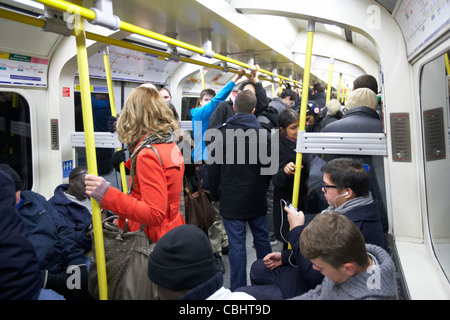 Mädchen mit roten Mantel stehend auf belebten u-Bahn umgeben von Menschen auf der London underground England Vereinigtes Königreich Vereinigtes Königreich Stockfoto