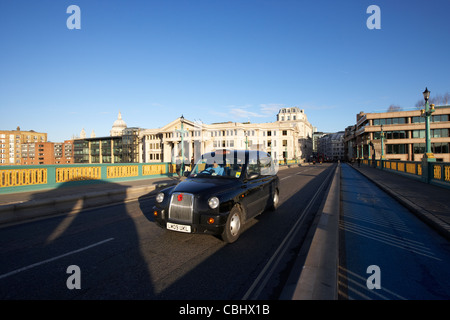 schwarzes Londoner Taxi Taxi Reisen über Southwark Bridge vorbei an leeren Fahrradweg in central London England Vereinigtes Königreich Großbritannien Stockfoto