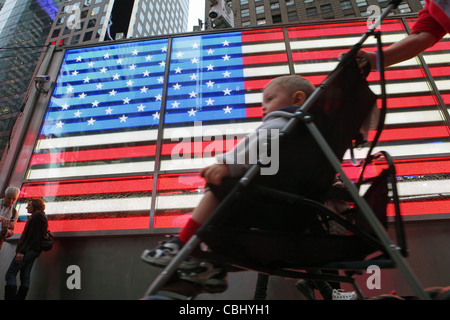 Kind im Kinderwagen zu vergangenen, Neon beleuchtet, Stars & Stripes, amerikanische Flagge, Times Square, Manhattan, New York City NYC USA Stockfoto