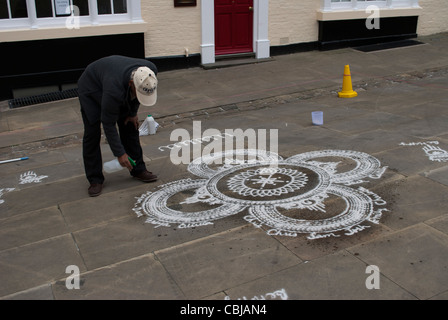 Erstellen von indischen Streetart (Kolam, Rangoli) aus weißem Marmor Pulver auf Steinpflaster Flaggen in Lincoln Mann Stockfoto