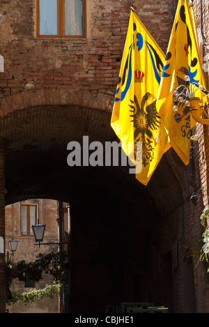 Gelbe Flaggen mit blauen und zurück Banner und einen doppelköpfigen Adler sind auf dem Display in Siena, Italien, ein Contrada darstellt. Stockfoto