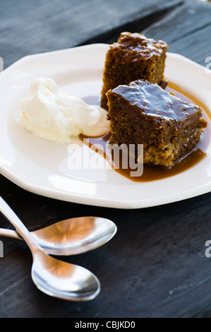 Sticky Toffee Pudding mit Eis und Löffel Stockfoto