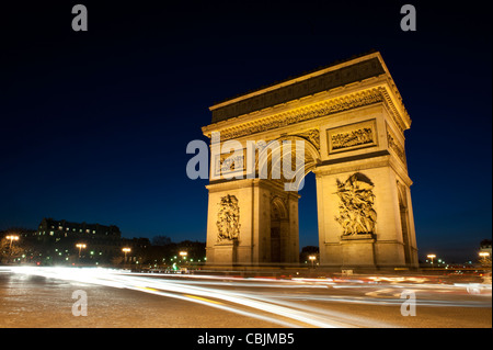 Der Arc de Triomphe aus dem umfassenden Kreisverkehr während des Abends, mit Licht Wege aus dem Verkehr. Stockfoto
