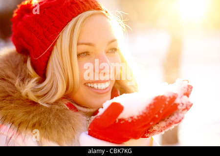 Porträt von glücklichen Mädchen hält Schnee auf Palmen mit Sonnenschein über Ihr Stockfoto