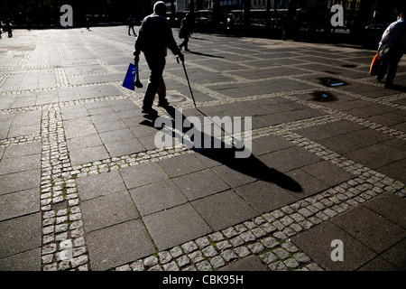 Silhouette der ältere Mann zu Fuß mit einem Rohrstock und Einkaufstasche, Köln Stockfoto