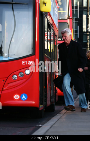 ein Mann läuft für einen Bus, der an einer Bushaltestelle wartet Stockfoto