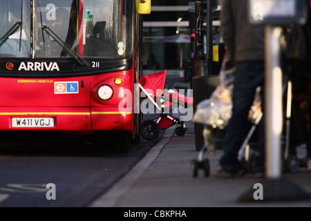 ein Kinderwagen, genommen aus einem roten Londoner Bus an einer Bushaltestelle Stockfoto