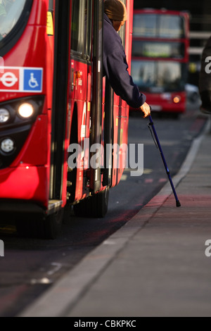 eine Person mit einem Gehstock immer aus einem roten Londoner Bus in London Stockfoto