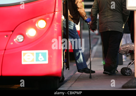 Eine Person mit einem Gehstock, einem roten Londoner Bus aussteigen Stockfoto