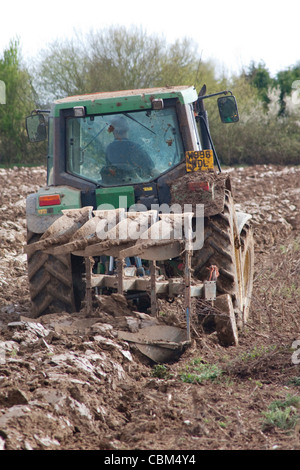Ein John Deere Traktor pflügen ein Feld in der Nähe von Porchfield auf der Isle Of Wight im Frühjahr. Stockfoto