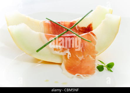 Köstliche geschnittene Melone und Speck auf weißen Teller Stockfoto