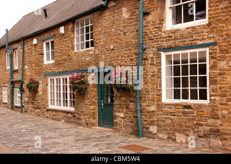 Terrassenförmig angelegten Reihe von schönen alten englischen Steinhütten in engen gepflasterten Straße, Oakham, Rutland, England, UK Stockfoto