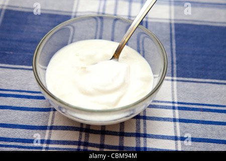 Joghurt in eine Schüssel mit Löffel auf Tisch Stockfoto