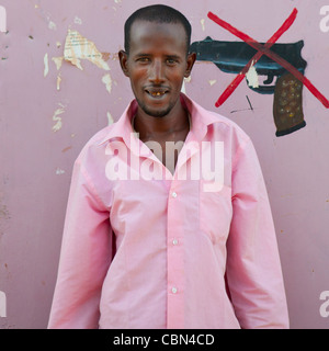 Anti-Waffe Schild an Wand gemalt, junger Erwachsener In rosa T-Shirt gegen Wand Burao, Somaliland Stockfoto