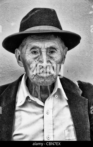 Alter Mann mit Falten und großen Augen helle Wand mit schwarzer Cowboy-Hut in touristischen Dorf von Antigua Guatemala Stockfoto