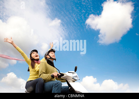 Glückliche junge Paare, die Spaß auf einem Roller Stockfoto