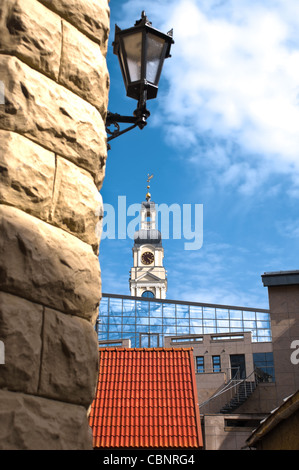 schöne Mischung aus moderne und alte Architektur im Zentrum von Riga, Lettland. Alte Lampe im Vordergrund und alten Turm mit modernen Stockfoto