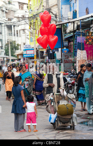 Indischer Mann Herz Luftballons in einer belebten indischen Straße zu verkaufen. Puttaparthi, Andhra Pradesh, Indien Stockfoto