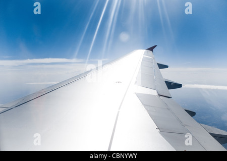 Blick auf blauen bewölkten Himmel und Erde mit Sonnenstrahlen schlagen Tragfläche im Vordergrund Stockfoto